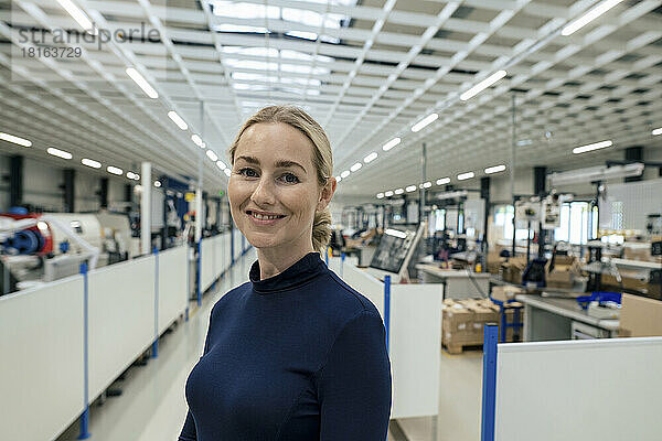 Lächelnde Geschäftsfrau mit blonden Haaren in der Fabrik