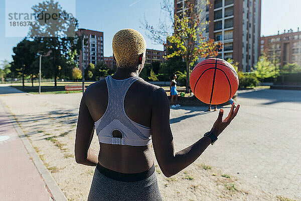 Junge Sportlerin spielt an sonnigem Tag Basketball