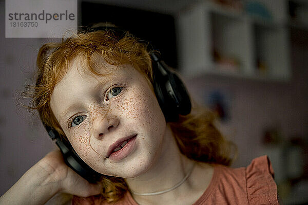 Mädchen mit kabellosen Kopfhörern hört zu Hause Musik