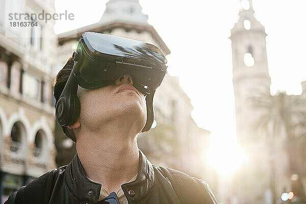 Junger Mann mit VR-Brille vor Gebäude