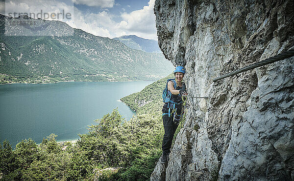 Glückliche Frau klettert auf den Berg mit dem Idrosee im Hintergrund