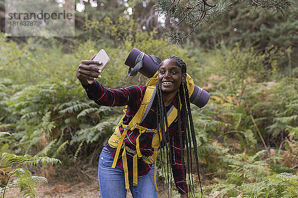 Glückliche junge Frau mit Rucksack  die ein Selfie mit dem Smartphone macht