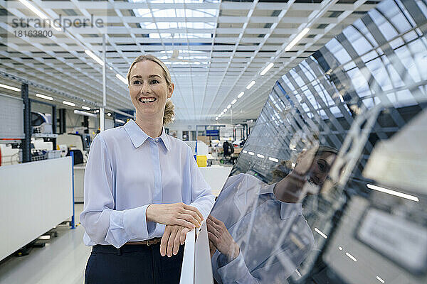 Happy businesswoman standing by desktop computer at industry