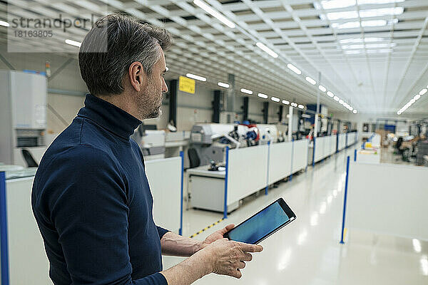 Geschäftsmann mit Tablet-PC steht in der Industrie