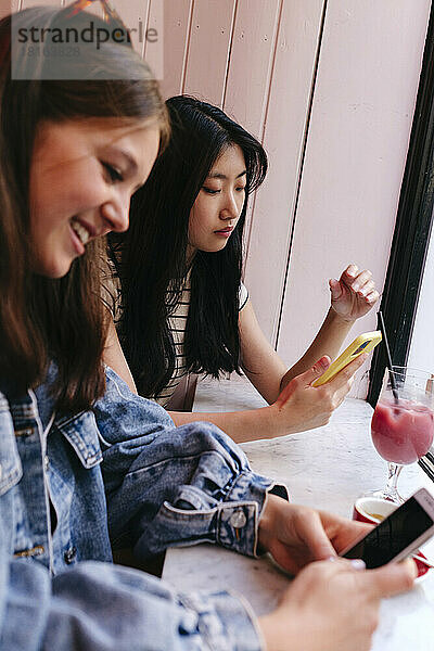 Lesbisches Paar benutzt Smartphones im Café