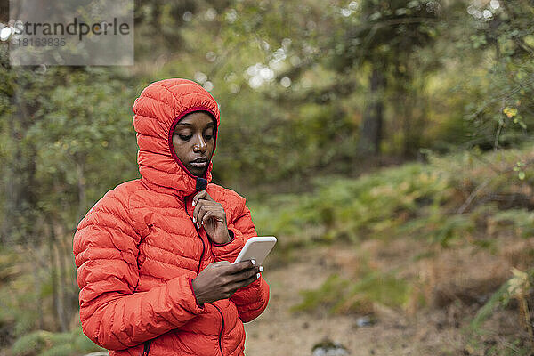 Junge Frau benutzt Smartphone im Wald