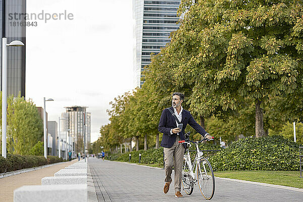 Geschäftsmann rollt mit Fahrrad auf Fußweg