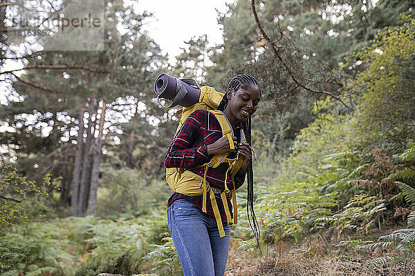 Glückliche Frau mit Rucksack spaziert im Wald