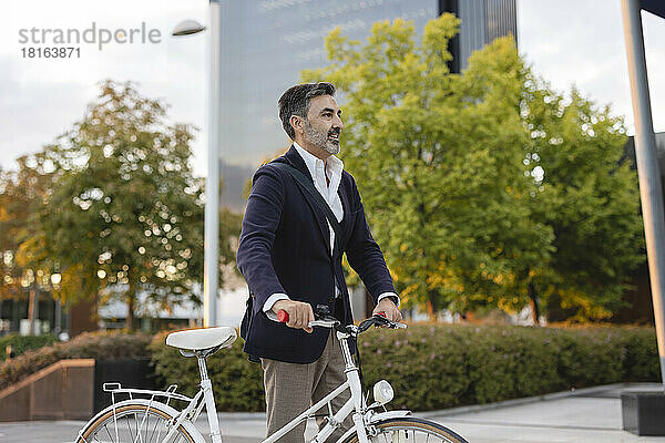 Mature businessman wheeling with bicycle