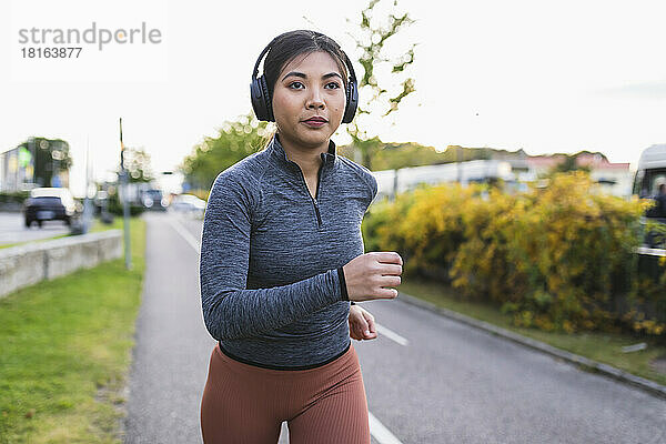 Junge Frau hört Musik und joggt auf der Straße