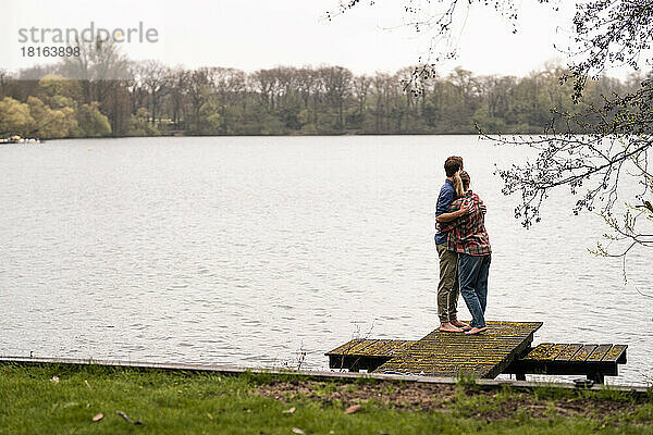 Liebevolles Paar blickt auf den See  der auf dem Steg steht