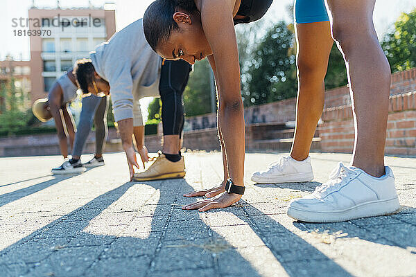 Junge Sportlerin übt Übungen mit Freunden auf dem Fußweg