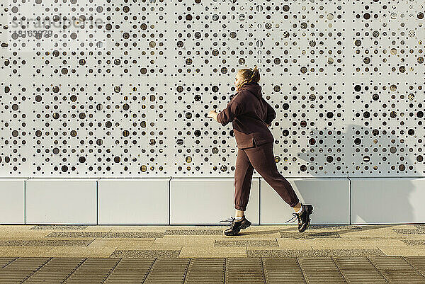 Plus-Size-Frau joggt an der Wand