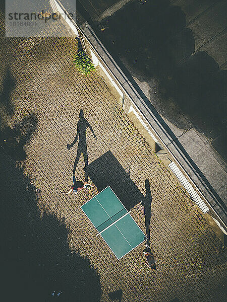 Reifer Mann mit Tochter spielt Tischtennis im Hinterhof