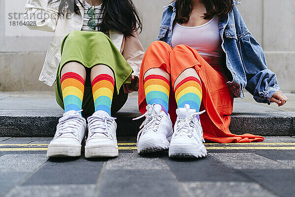 Lesbische Frauen in bunten Socken sitzen auf dem Fußweg
