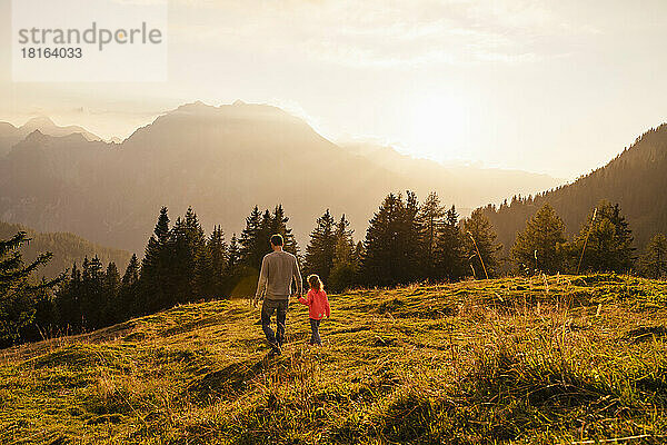 Vater hält Tochter an der Hand und läuft über Gras