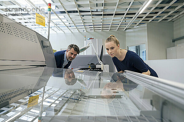 Junge Geschäftsfrau und Geschäftsmann untersuchen 3D-Druckmaschine