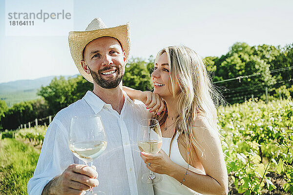 Glückliches Paar mit Wein  das zusammen im Weingut steht