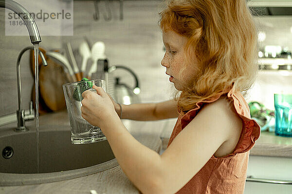 Mädchen wäscht Glas in der Küche