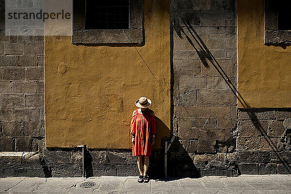 Frau mit Sonnenhut vor brauner Wand