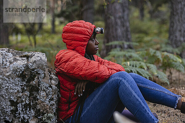 Junge Frau mit Taschenlampe sitzt im Wald
