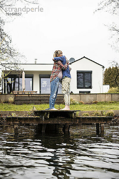 Werdendes Paar umarmt sich auf dem Steg vor dem Haus