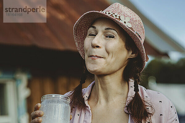 Frau mit Fischerhut trinkt frische Milch
