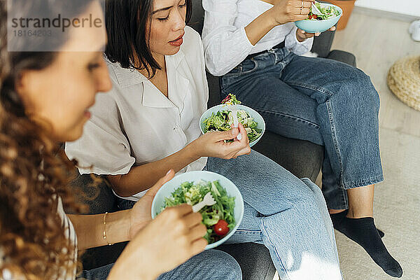 Gemischtrassige Mitbewohner essen zu Hause Salat zum Mittagessen
