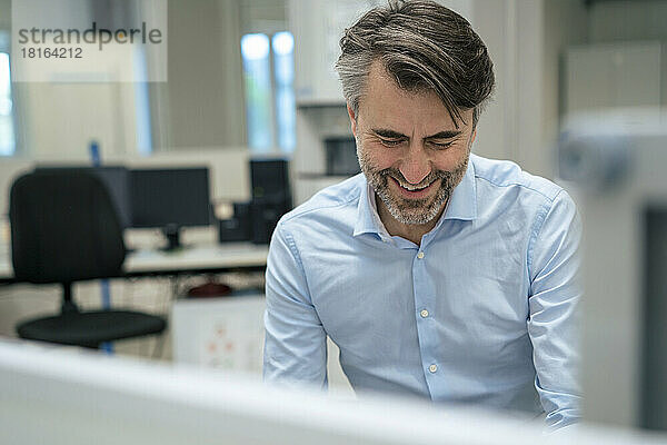 Happy mature businessman at desk in office