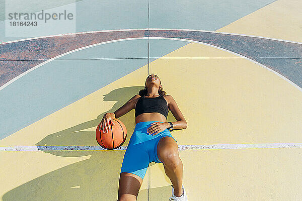 Basketball player lying with ball on court