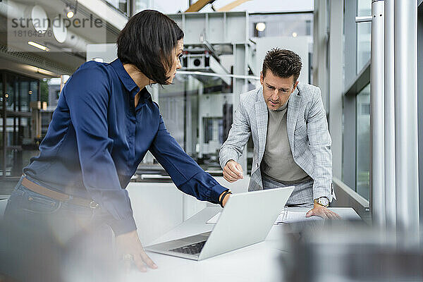 Geschäftsmann und Geschäftsfrau diskutieren über Laptop am Schreibtisch