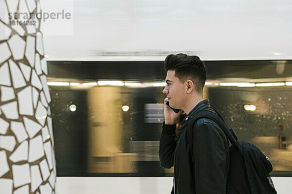 Junger Mann telefoniert am Bahnhof