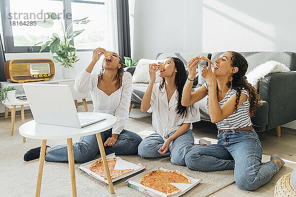Junge Mitbewohner essen zu Hause Pizzastücke