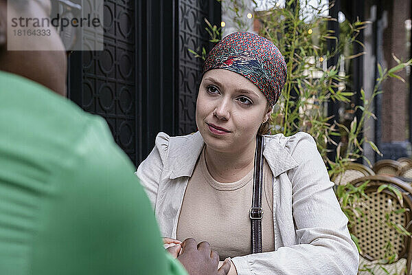 Frau mit Kopftuch unterhält sich mit Freundin im Straßencafé