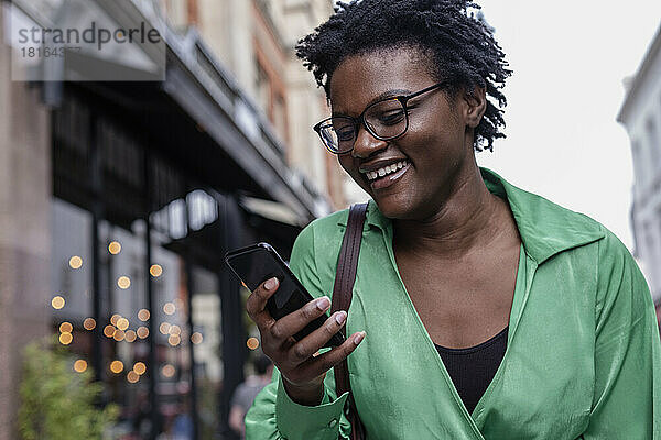 Happy young woman using smart phone in city