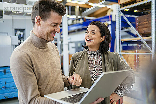 Lächelnder Geschäftsmann mit Laptop und Geschäftsfrau in der Industrie