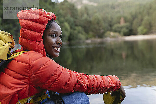 Lächelnde Frau sitzt vor dem See