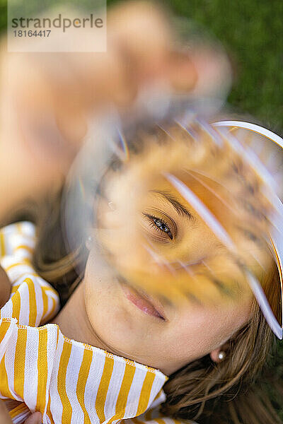 Mädchen mit Sonnenblende schaut durch Objekt