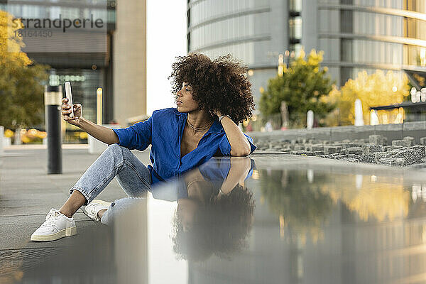 Afro-Frau macht ein Selfie mit ihrem an die Wand gelehnten Mobiltelefon