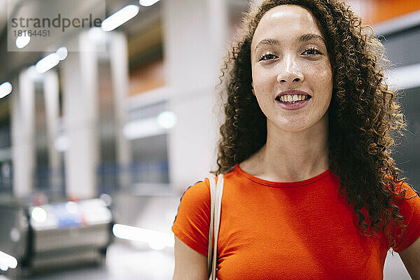 Glückliche Frau mit lockigem Haar an der U-Bahn-Station