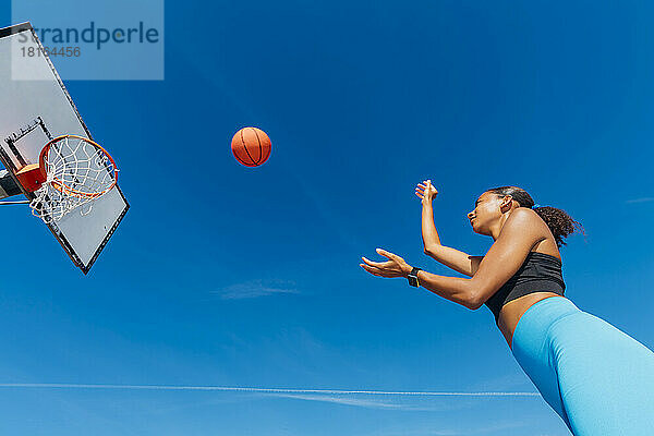 Sportlerin wirft an sonnigem Tag Basketball im Korb