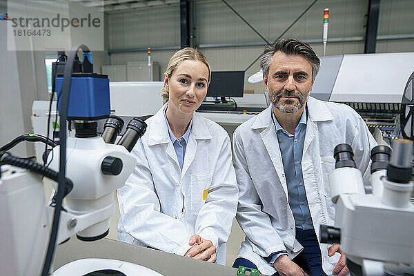 Lächelnde Wissenschaftler im Laborkittel sitzen in der Industrie