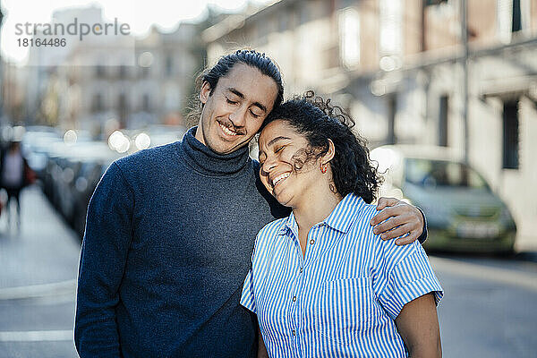 Lächelndes Paar träumt gemeinsam mit geschlossenen Augen auf der Straße