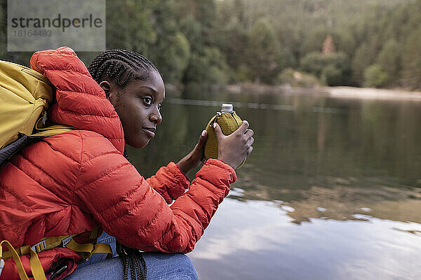 Junge Frau mit Wasserflasche sitzt vor dem See