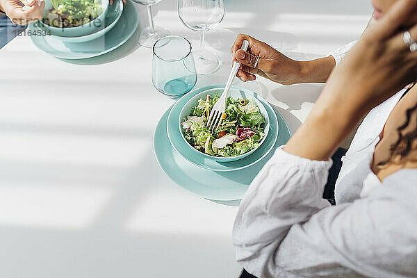 Frau isst zu Hause Salat zum Mittagessen