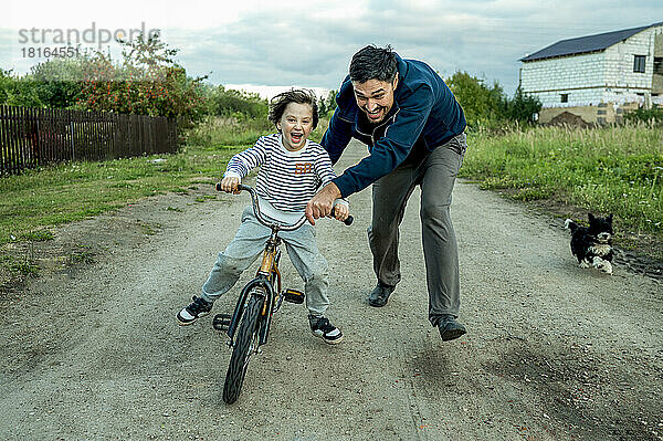 Glücklicher Vater bringt seinem Sohn das Fahrradfahren bei