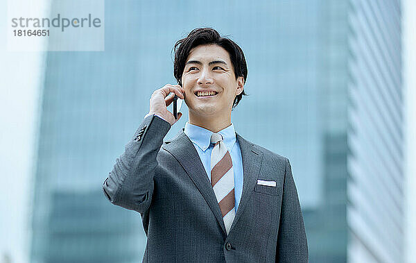 Japanischer Geschäftsmann spricht auf Smartphone
