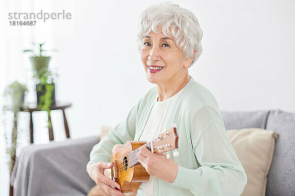 Japanische Seniorin spielt Ukulele