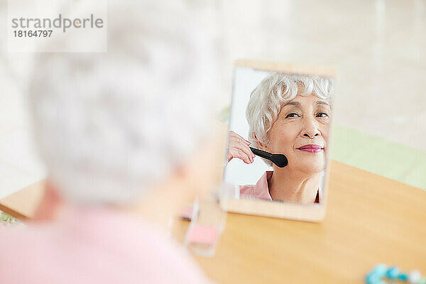 Japanische ältere Frau  die Make-up aufträgt