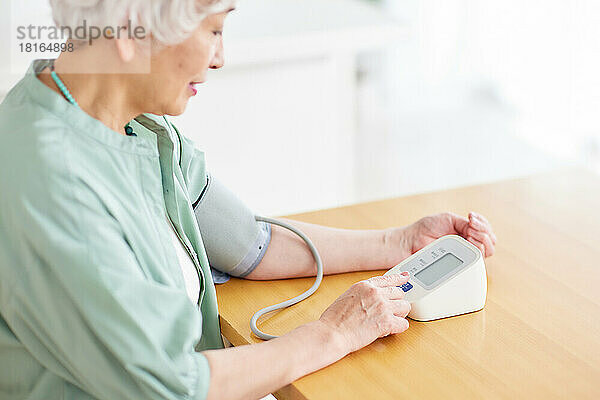 Ältere japanische Frau misst den Blutdruck
